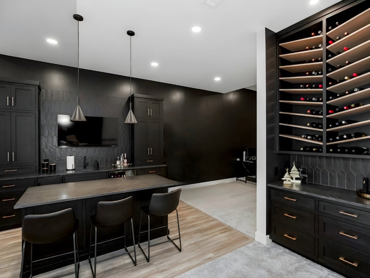 Finished basement entertainment lounge with black cabinetry and wine storage